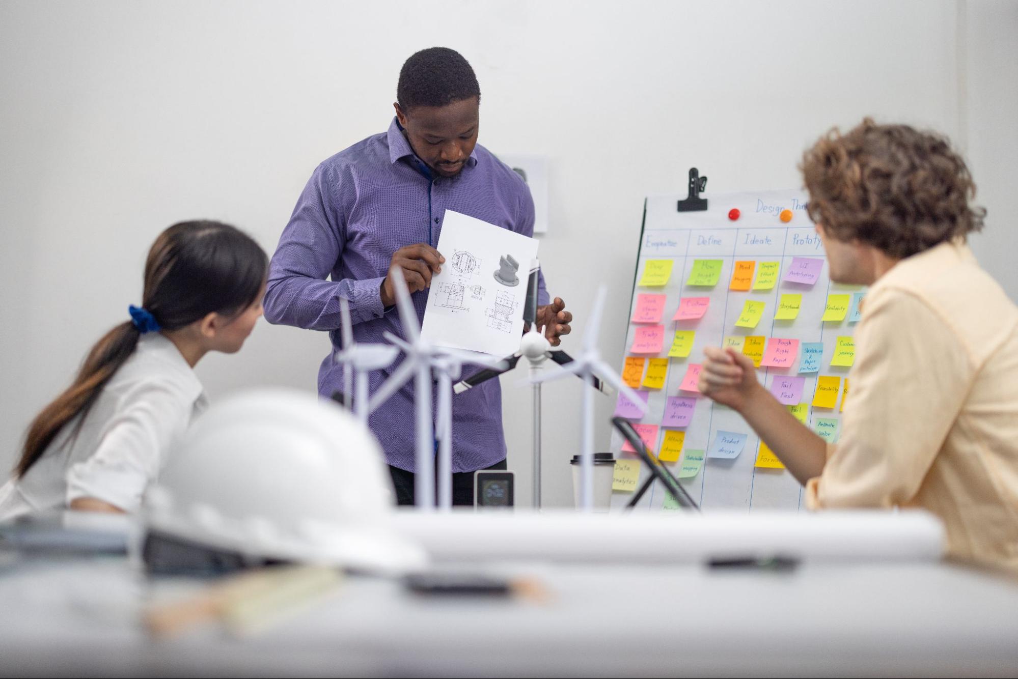 A diverse startup team works on a product development process for a portable wind turbine prototype to meet user demand and attract investor funding.