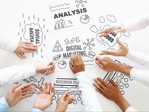 Several hands point to multiple factors to consider in a marketing analysis, including various diagrams and charts.