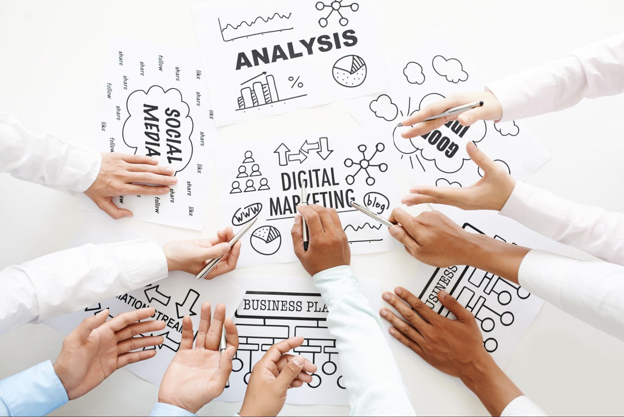 Several hands point to multiple factors to consider in a marketing analysis, including various diagrams and charts.