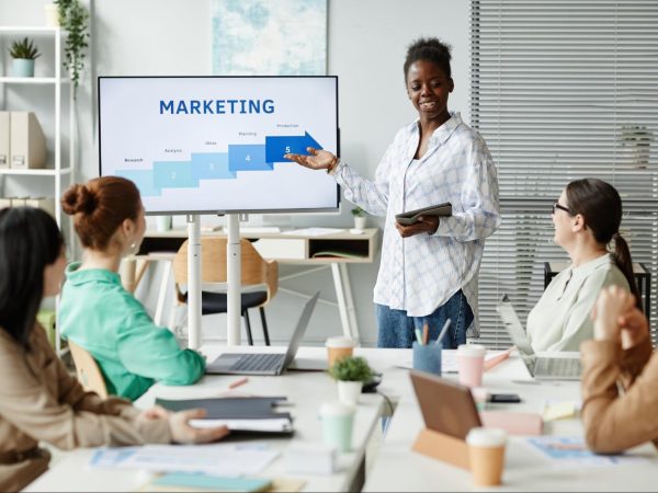 A female marketing consultant discussing a crucial topic about marketing with a prepared presentation to coworkers.