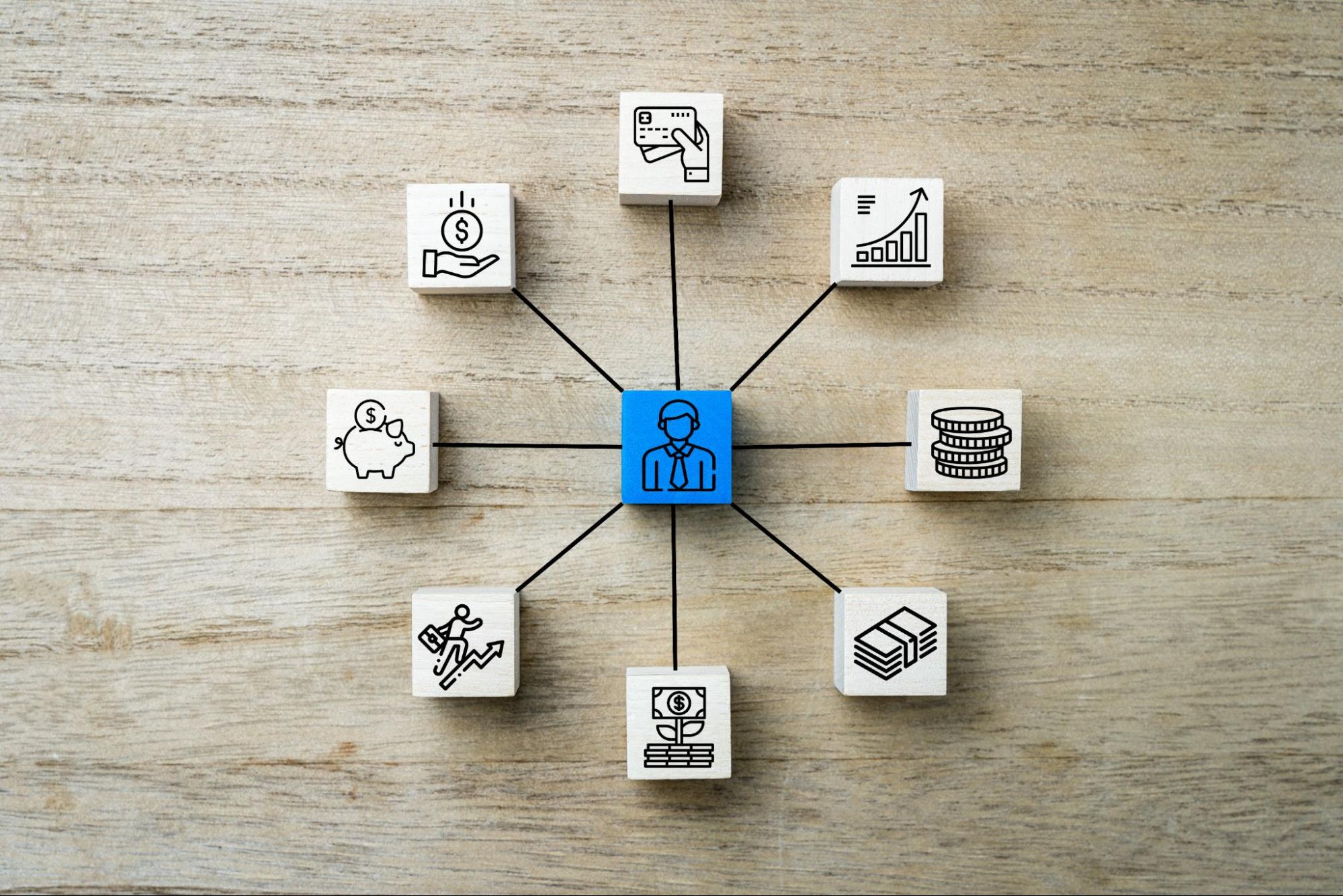 White blocks displaying various resource allocation icons connected to a central blue block with a businessman icon, symbolizing strategic financial planning.