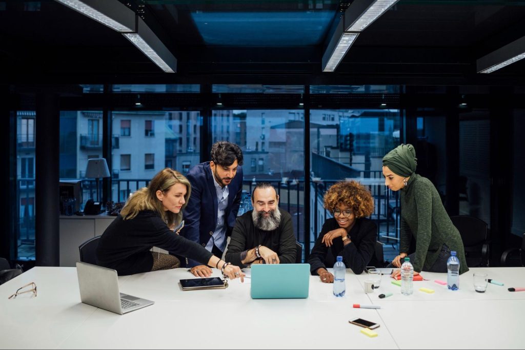 Startup partners in a brainstorming session at a modern office table, with laptops, tablets, phones, and a water bottle visible, fostering a collaborative vibe.